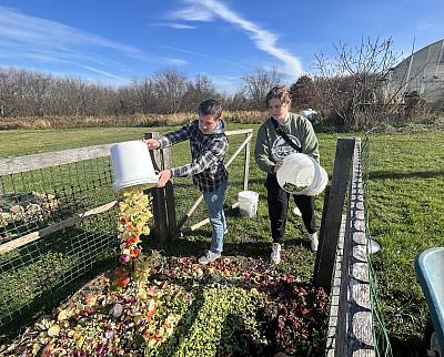 在萨斯奎哈纳校园花园，26岁的莎拉·乔伊和24岁的帕特里克·克罗斯把消费前的食物垃圾扔进堆肥箱.